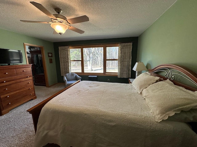 carpeted bedroom with a closet, a textured ceiling, ceiling fan, and a walk in closet