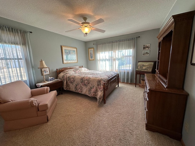 carpeted bedroom with ceiling fan, a textured ceiling, and multiple windows