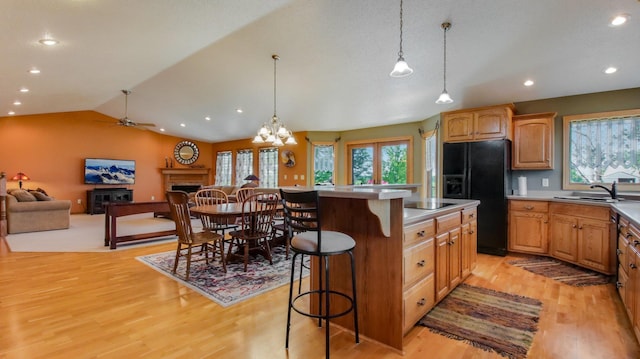 kitchen with black appliances, a kitchen bar, a center island, and pendant lighting