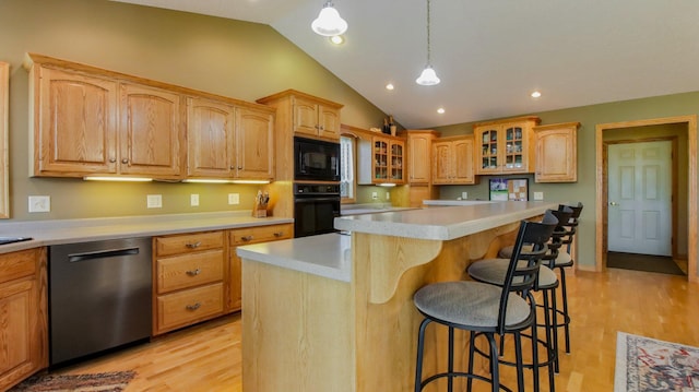 kitchen with light wood-type flooring, a kitchen breakfast bar, lofted ceiling, black appliances, and a center island