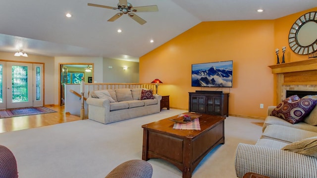 living room featuring french doors, vaulted ceiling, ceiling fan, light colored carpet, and a tile fireplace