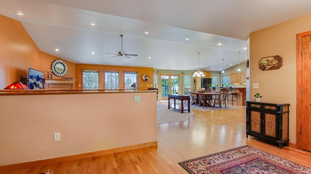 kitchen with pendant lighting, light hardwood / wood-style floors, a textured ceiling, high vaulted ceiling, and ceiling fan with notable chandelier