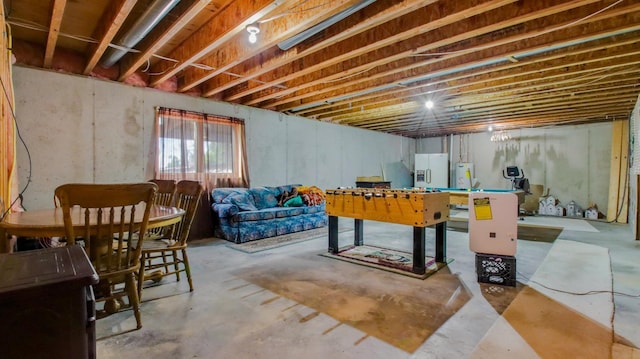 basement featuring water heater and refrigerator with ice dispenser