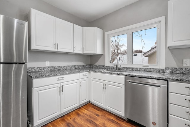 kitchen with dark hardwood / wood-style floors, stainless steel appliances, white cabinetry, and sink