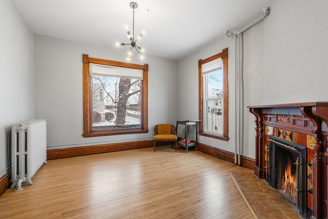 living area with a healthy amount of sunlight, light hardwood / wood-style flooring, a tile fireplace, and radiator heating unit