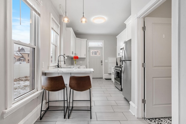 kitchen with white cabinets, appliances with stainless steel finishes, sink, and pendant lighting