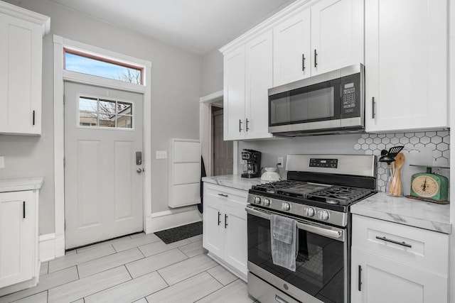 kitchen featuring light stone countertops, appliances with stainless steel finishes, and white cabinetry