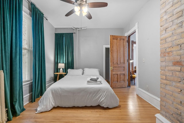 bedroom with ceiling fan, brick wall, and light hardwood / wood-style floors