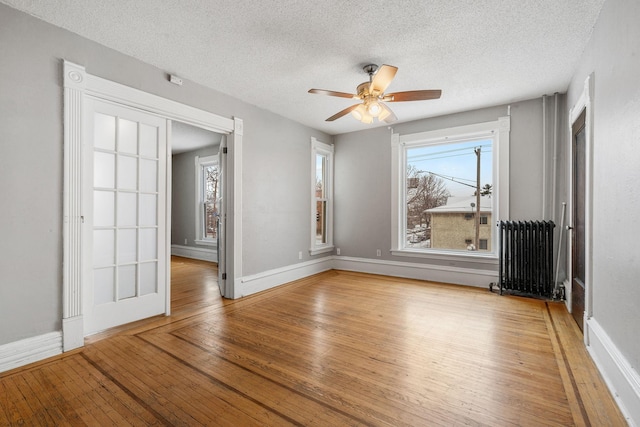 spare room with wood-type flooring, radiator, and a textured ceiling