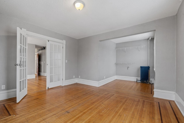 unfurnished bedroom featuring radiator, a closet, hardwood / wood-style floors, and french doors