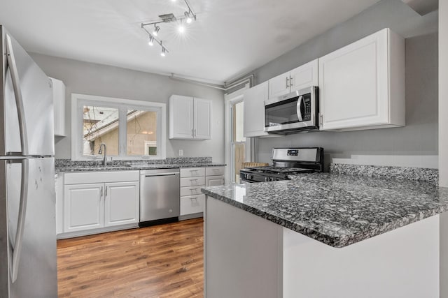 kitchen with light hardwood / wood-style floors, kitchen peninsula, stainless steel appliances, white cabinets, and sink