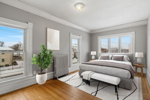 bedroom with radiator, multiple windows, and light hardwood / wood-style floors