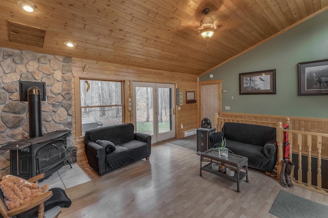 living room with a wood stove, ceiling fan, wooden ceiling, light hardwood / wood-style flooring, and vaulted ceiling