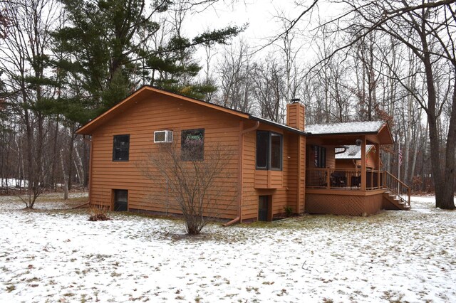 snow covered back of property featuring covered porch