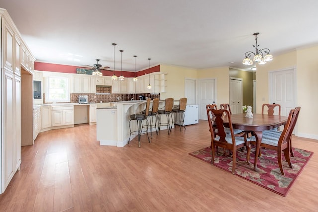 dining area featuring ornamental molding, ceiling fan with notable chandelier, and light hardwood / wood-style flooring