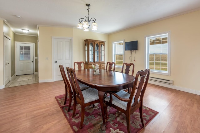 dining area with an inviting chandelier, a baseboard heating unit, crown molding, and light hardwood / wood-style flooring