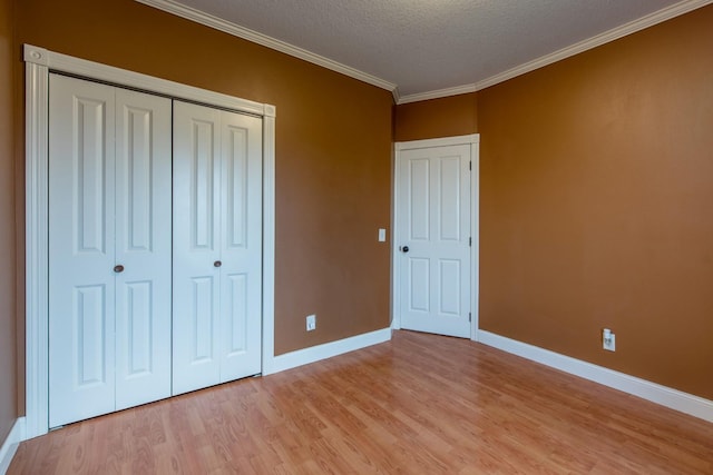 unfurnished bedroom featuring crown molding, light hardwood / wood-style floors, a closet, and a textured ceiling