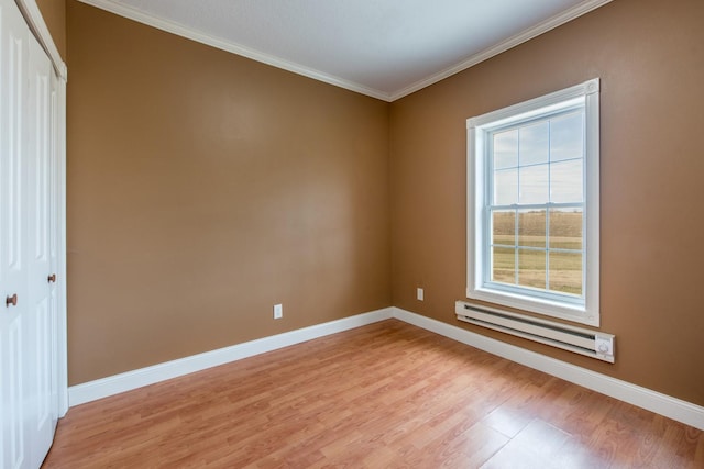 empty room with baseboard heating, ornamental molding, and light wood-type flooring