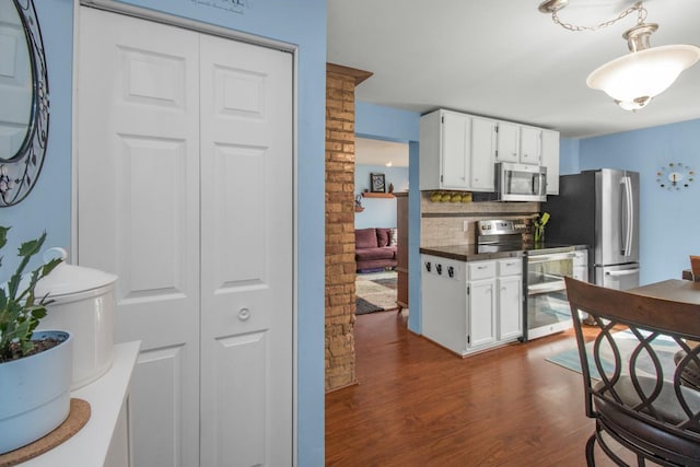 kitchen with decorative backsplash, dark wood-type flooring, white cabinets, and stainless steel appliances