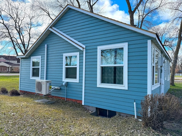 view of side of home featuring ac unit and a yard