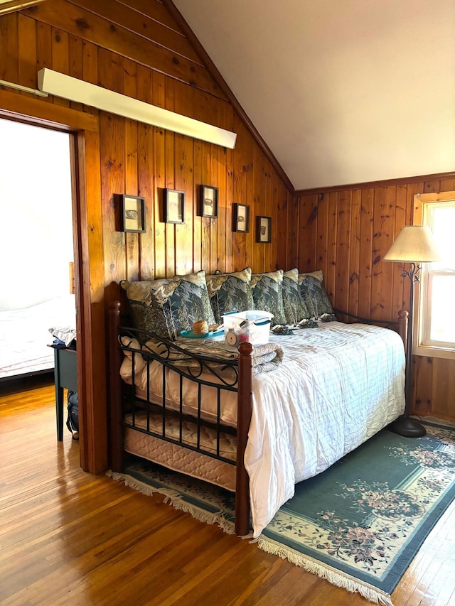 bedroom with lofted ceiling, wood walls, and wood-type flooring