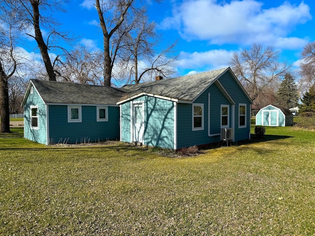 view of property exterior with an outbuilding, a yard, roof with shingles, and a chimney