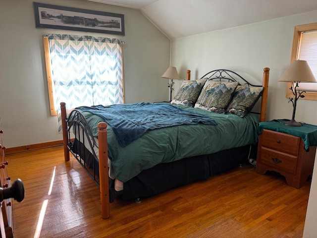 bedroom featuring lofted ceiling, baseboards, and wood finished floors