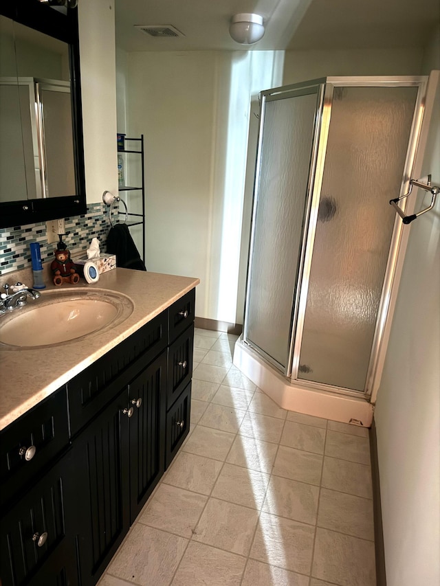 bathroom with backsplash, a stall shower, vanity, baseboards, and tile patterned floors