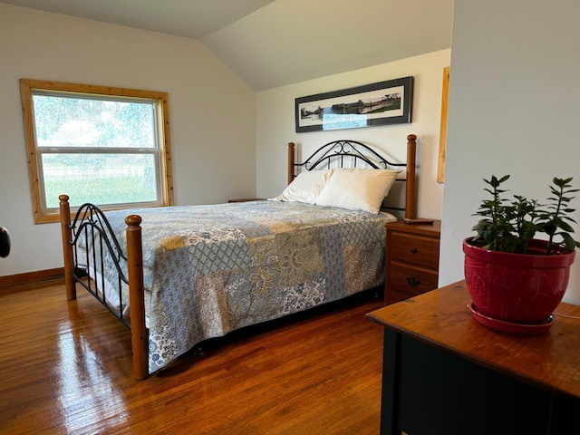 bedroom with lofted ceiling, baseboards, and wood finished floors