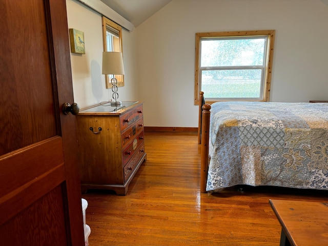 bedroom featuring baseboards, vaulted ceiling, and wood finished floors