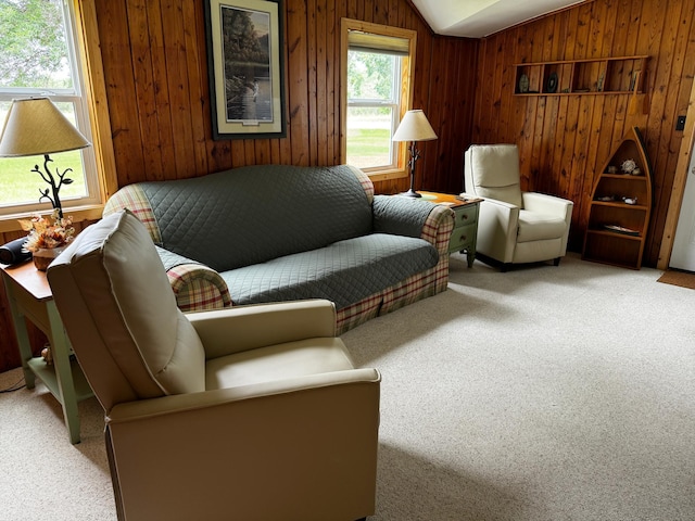 sitting room featuring carpet floors, wooden walls, and vaulted ceiling