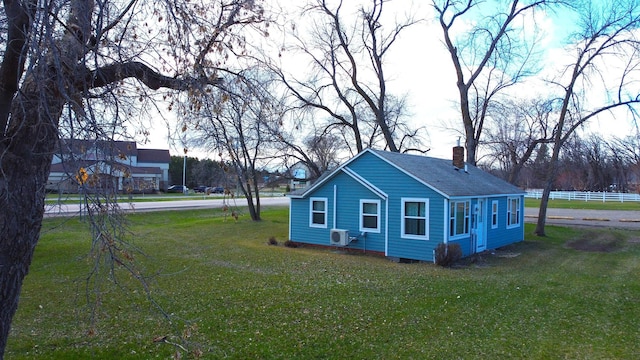 view of side of property featuring a yard, a shingled roof, and a chimney