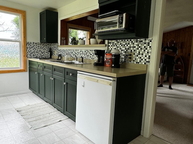 kitchen featuring a healthy amount of sunlight, white dishwasher, a sink, and decorative backsplash