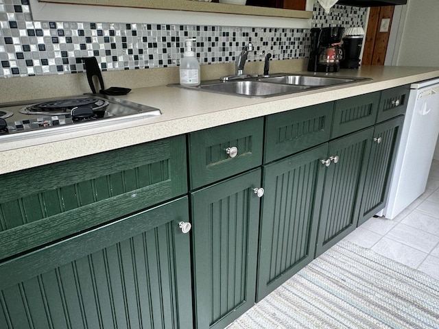 kitchen featuring dishwashing machine, a sink, stainless steel stovetop, green cabinets, and tasteful backsplash