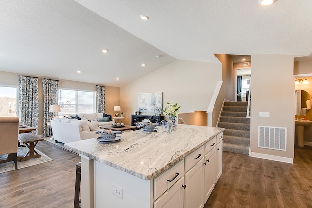 kitchen featuring lofted ceiling, white cabinetry, dark wood-type flooring, and a kitchen island