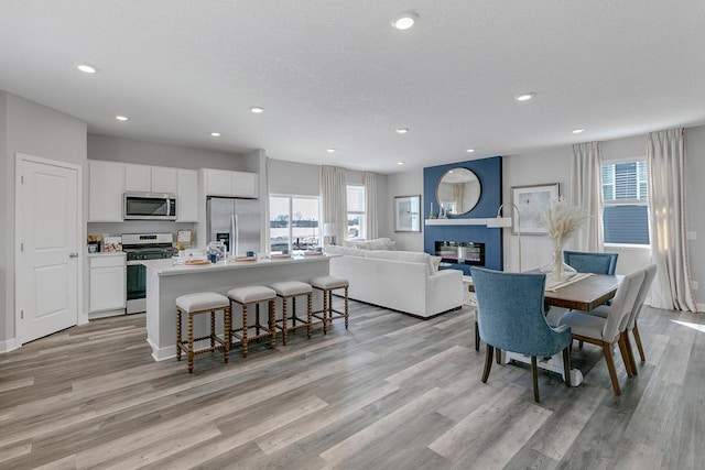 dining space with light hardwood / wood-style floors and a textured ceiling