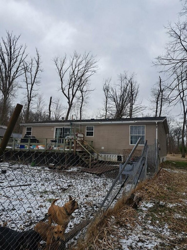 snow covered back of property featuring a deck