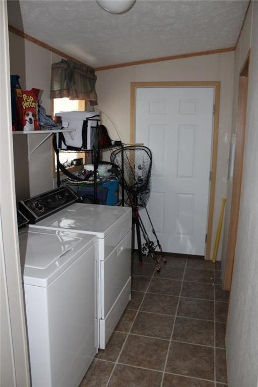 laundry room featuring washer and clothes dryer, a textured ceiling, dark tile patterned flooring, and crown molding