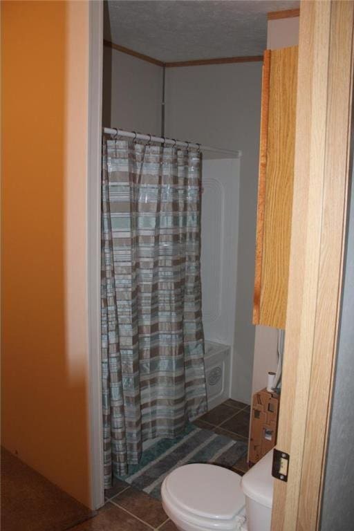 bathroom featuring a textured ceiling, tile patterned flooring, and toilet