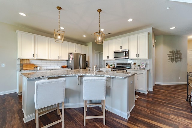 kitchen featuring an island with sink, dark hardwood / wood-style floors, appliances with stainless steel finishes, and white cabinetry