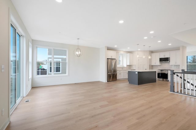 unfurnished living room with an inviting chandelier and light wood-type flooring