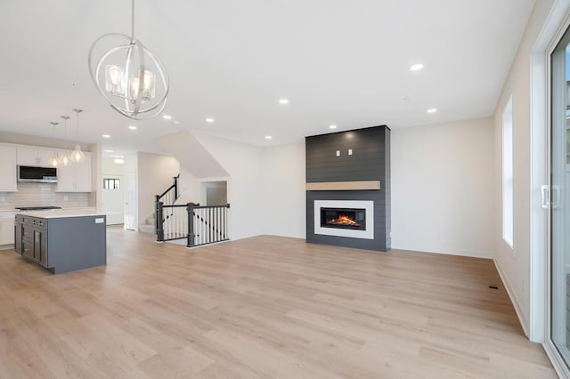 unfurnished living room featuring a chandelier, light wood-type flooring, and a fireplace