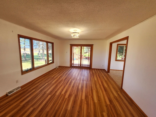 empty room featuring a textured ceiling and dark hardwood / wood-style flooring