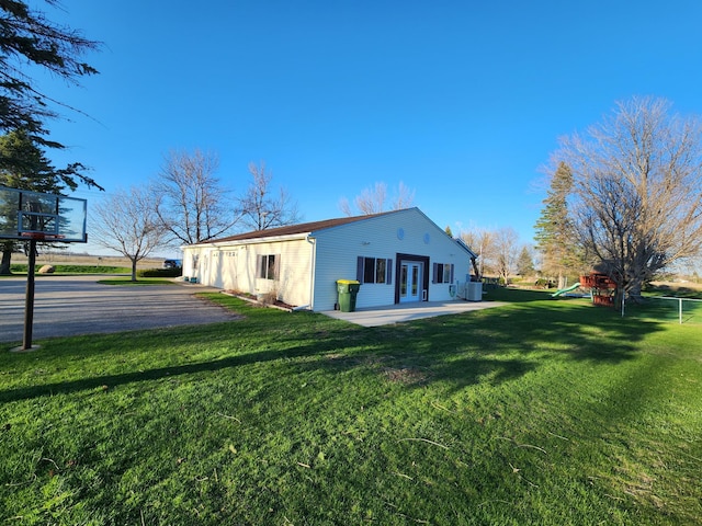 view of side of home featuring a yard, a playground, a patio area, and central air condition unit