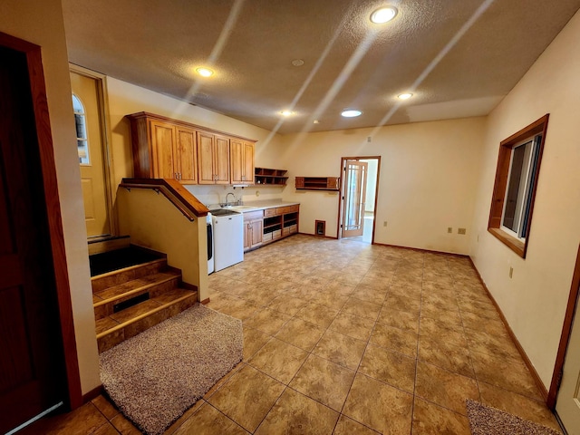 kitchen featuring a textured ceiling, dishwasher, and sink