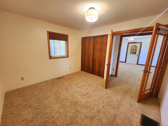 unfurnished bedroom featuring light carpet and a closet