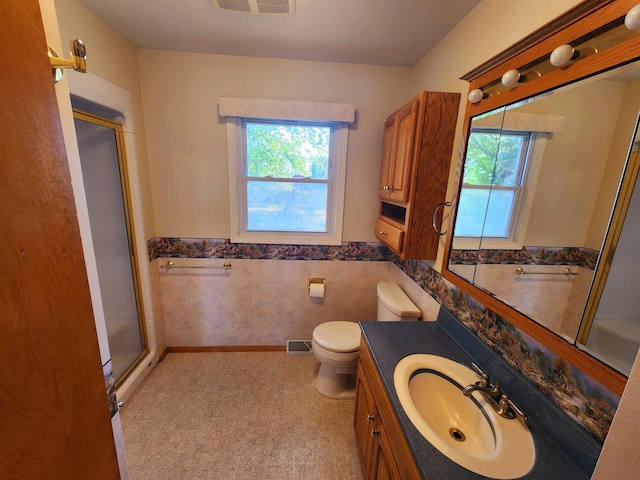 bathroom featuring a shower with door, vanity, and toilet