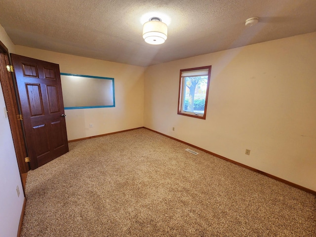 carpeted empty room with a textured ceiling