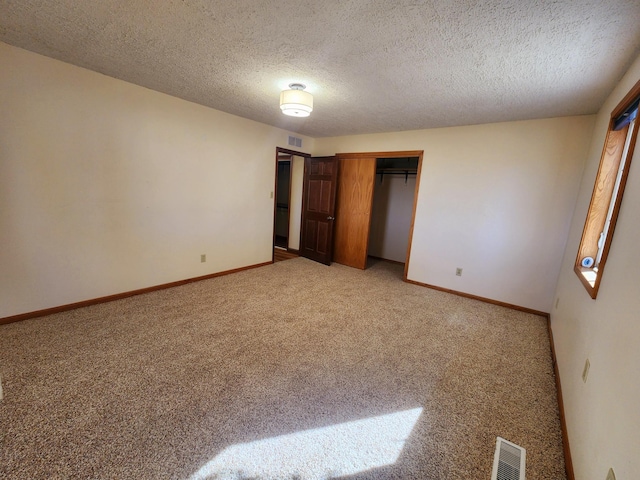 unfurnished bedroom featuring light carpet, a closet, and a textured ceiling