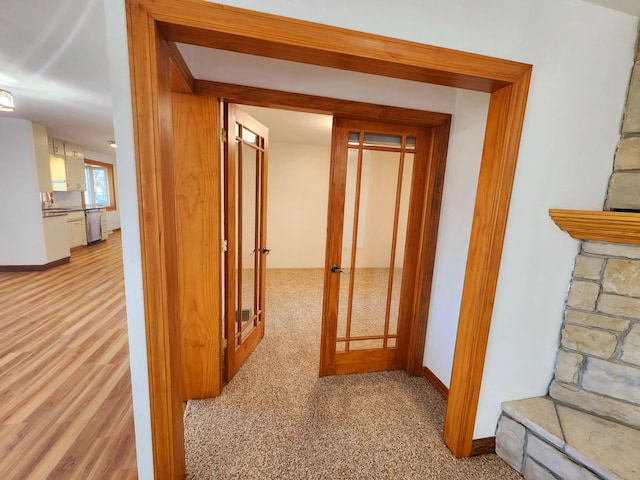 corridor featuring french doors, baseboards, and wood finished floors